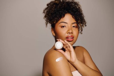 A beautiful young African American woman with curly hair in a studio setting, applying a thick layer of cream clipart