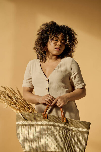 A beautiful young African American woman with curly hair holding a basket with a handle in a studio setting.
