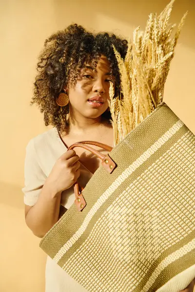 小麦の束で満たされた袋を保持するカーリーヘアの美しい若いアフリカ系アメリカ人女性 — ストック写真