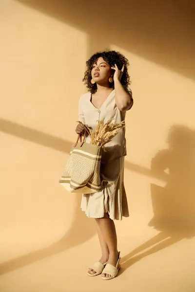 一位衣着时髦 一头卷发的非洲裔美国女人站在那里 提着一个穿着华丽夏装的袋子 — 图库照片