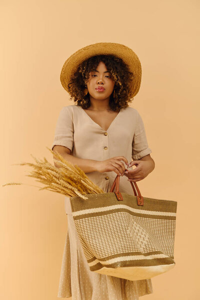 A young African American woman with curly hair, dressed in a summer dress, holding a bag while wearing a straw hat.