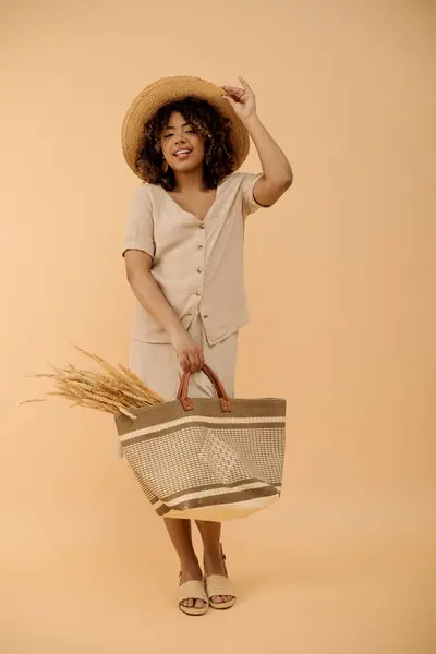 Stock image A beautiful young African American woman with curly hair, wearing a hat and dress, holds a basket in a studio setting.