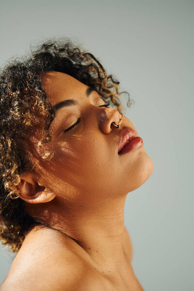 A beautiful African American woman with curly hair poses actively on a vibrant backdrop.