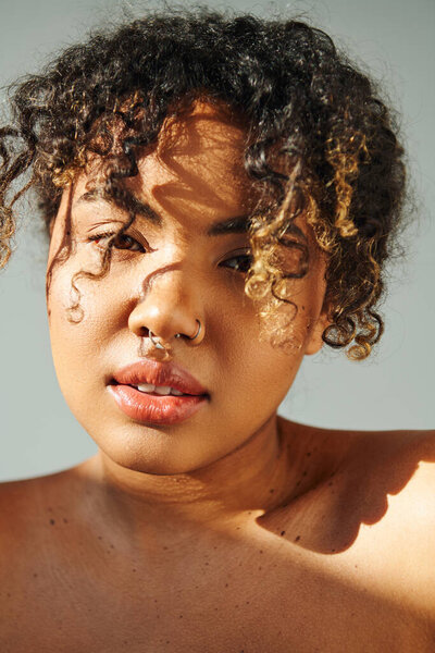 Красивая афроамериканка с вьющимися волосами, активно позирующая на ярком фоне.