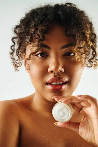 stock image Attractive African American woman showcasing cream jar.
