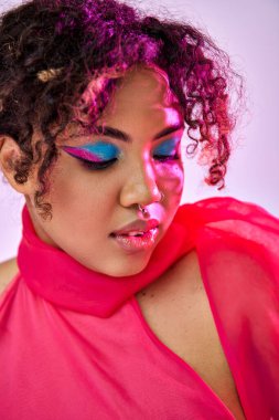 Güzel bir Afro-Amerikalı kadın açık makyajlı pembe bir elbiseyle aktif olarak poz veriyor..