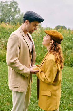 Bir erkek ve bir kadın, yemyeşil bir arazide sevgi dolu bir şekilde duruyor, sakin bir doğal ortamda romantik bir buluşmanın tadını çıkarıyorlar..