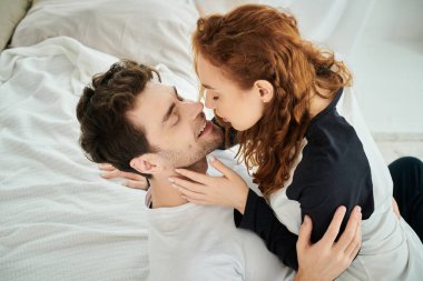 Bir erkek ve bir kadın yatak odasında bir yatakta uzanırken barışçıl bir şekilde kucaklaşıyorlar..