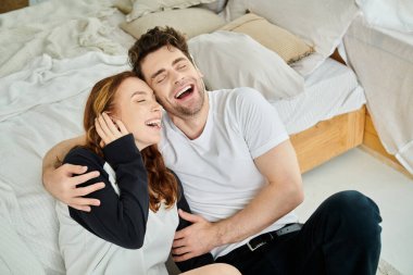 Bir erkek ve bir kadın, sıcak ve samimiyetle çevrili bir şekilde yataklarında, derin bir sohbetin içinde, huzurlu bir anın tadını çıkarırlar..