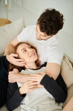 Bir erkek ve bir kadın sıcak bir kanepede sarılıp birbirlerine eşlik ediyorlar..