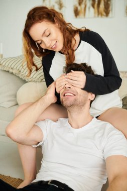 Bir erkek ve bir kadın sıcak ve samimi bir ortamda rahat bir kanepede yan yana otururlar..