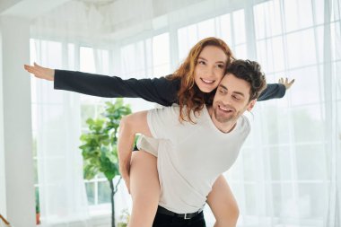 A man gracefully carries a woman on his back in a tender and intimate moment between the couple. clipart