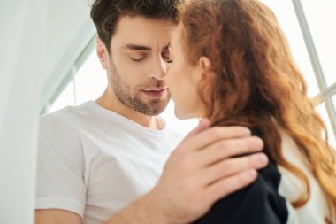 Bir erkek ve bir kadın yan yana durur, huzur dolu bir yatak odasında birlik ve bağ yayarlar..