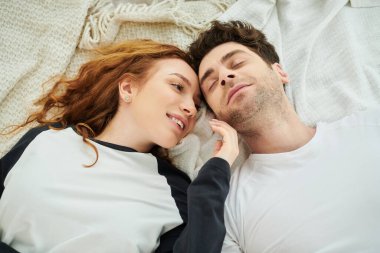 A man and a woman lay cuddled together on a bed, their loving connection evident in their relaxed poses. clipart