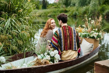 A stylish couple enjoying a romantic boat ride surrounded by vibrant flowers in a lush green park. clipart