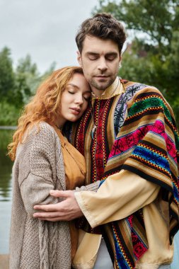 Boho kıyafetleri giymiş şık bir çift yeşil park ortamında yan yana durur, sevgi ve bağlılık yayarlar..