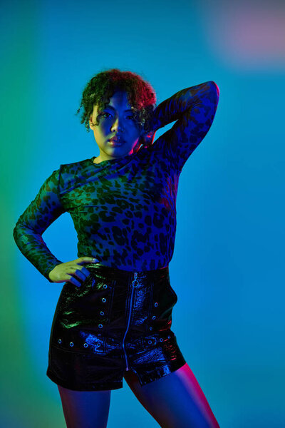 An active African American woman striking a pose in a leopard print shirt and black shorts.