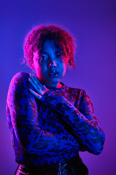 Vibrant African American woman with curly hair actively posing on backdrop.