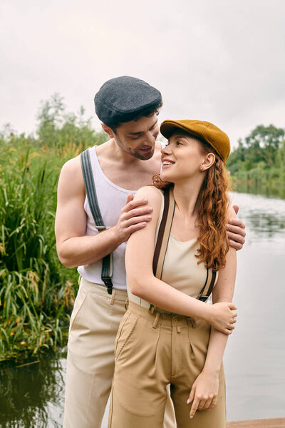 A man and woman enjoy a romantic evening together by a peaceful lake in a green park.