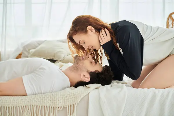 stock image A man and a woman in a warm embrace, lying on a comfortable bed in a bedroom, enjoying each others company.