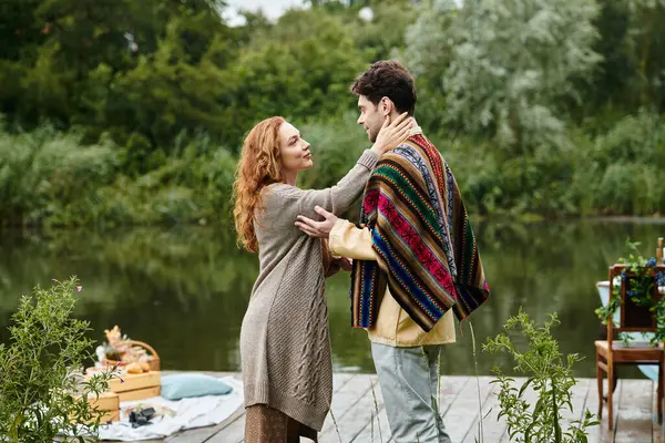 stock image A man and a woman, dressed in boho style clothing, stand side by side in a lush green park, creating a romantic scene.