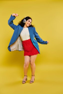 A young brunette woman with curly hair emoting in a stylish blue jacket and red skirt against a bright yellow background. clipart