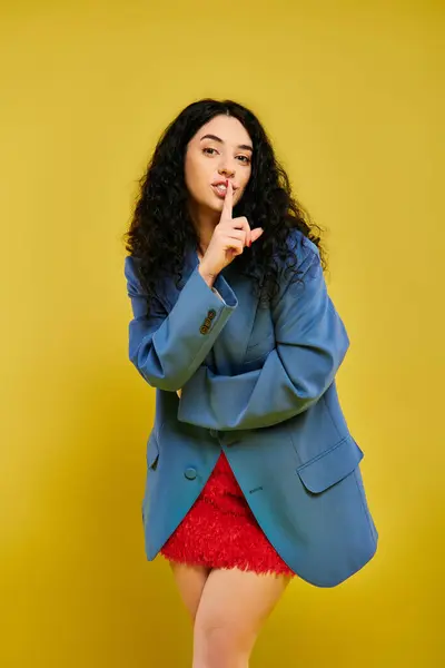 stock image A young, curly-haired brunette woman poses in stylish attire, expressing various emotions in front of a vibrant yellow wall.