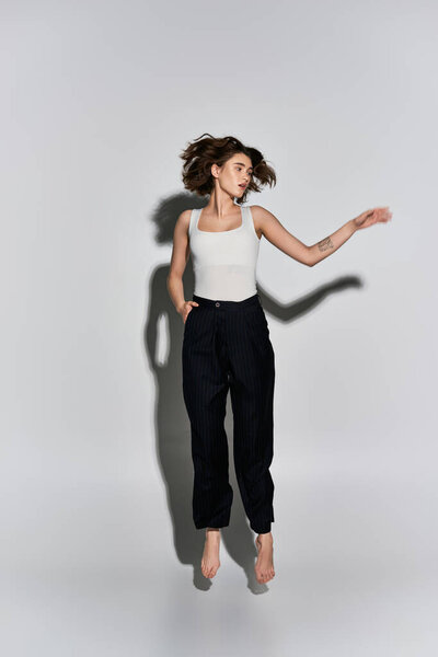 A stylish young woman with arm outstretched, exuding grace in an elegant attire