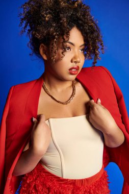 Zarif, şık, afro-amerikan kadın modeller canlı kıyafetlerle mavi arka plana bakıyorlar.