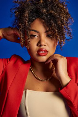 Çekici bir Afrikalı Amerikalı kadın. Canlı, şık giyinmiş, kameraya bakıyor.