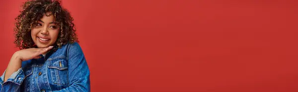 Радостный Привлекательный Африканский Американец Джинсовой Одежде Глядя Сторону Красном Фоне — стоковое фото