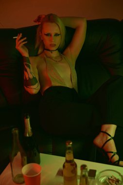 Kanepede oturmuş sigara içen bir kadın.