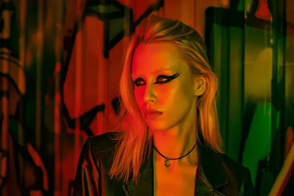 stock image Woman wearing black leather jacket standing amongst red and green lights at a rave-party