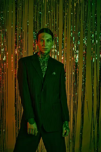 Perdenin önünde duran takım elbiseli bir adam.