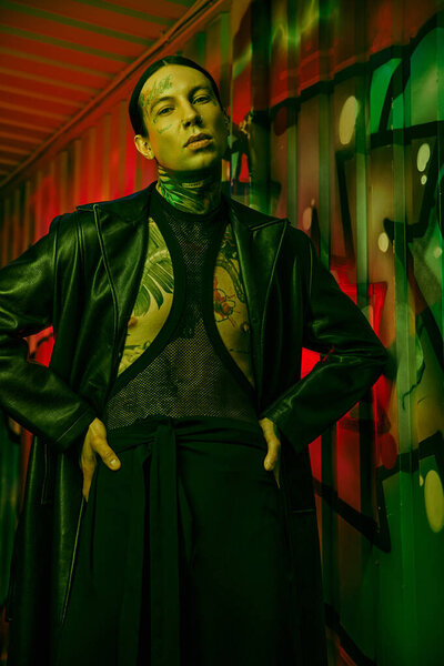 A man dressed in a black jacket and tie standing in front of a wall