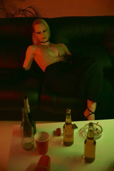 Bir Kadın Kanepede Çeşitli Alkol Şişelerinin Yanında Oturuyor — Stok fotoğraf