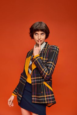 student with short hair posing in stylish checkered blazer on orange background, college uniform clipart