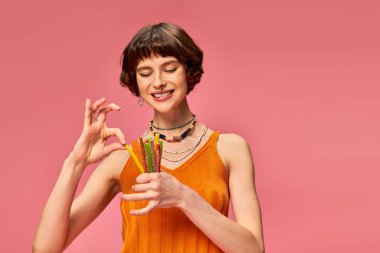 Mutlu piercing 'li kadın 20' li yaşlarında gülümsüyor ve elinde pembe ellerde bir demet tatlı ve ekşi şeker tutuyor.