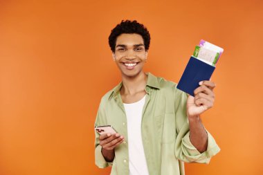 Çekici, Afro-Amerikalı bir adam elinde telefon ve pasaport, elinde bilet ve kameraya gülümsüyor.