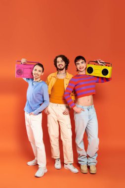 three cheerful appealing gay friends in vivid attire posing with tape recorders, pride month clipart