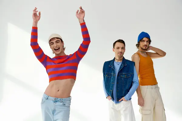 stock image stylish joyous lgbtq friends in vivid attires posing actively on gray backdrop and looking at camera