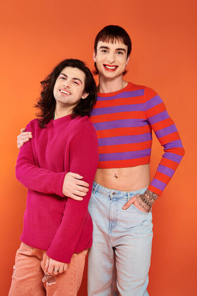 attractive stylish jolly gay friends in vibrant clothes posing happily together, pride month