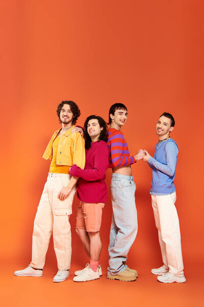 four debonair appealing cheerful gay men in vibrant clothes posing together actively, pride month