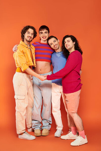 four trendy appealing cheerful gay men in vibrant clothes posing together actively, pride month