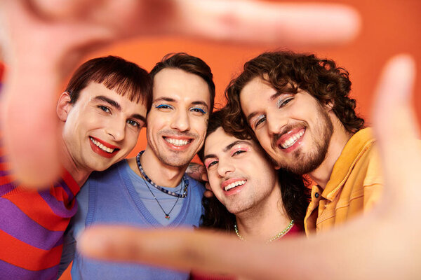 four stylish appealing cheerful gay men in vibrant clothes posing together actively, pride month