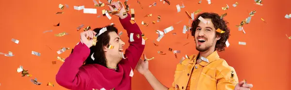 Весело Стильные Геи Ярких Одеждах Веселятся Конфетти Дождь Оранжевом Фоне — стоковое фото