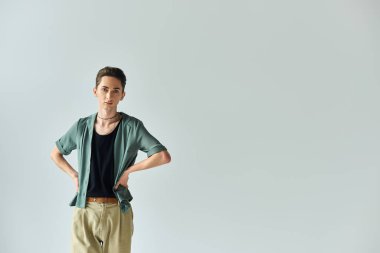 A young queer person strikes a pose in front of a white background, exuding confidence and pride as a member of the LGBTQ+ community. clipart