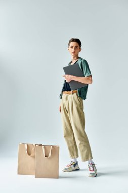 A young man confidently juggles shopping bags and a tablet computer, showcasing his fashionable and tech-savvy side. clipart