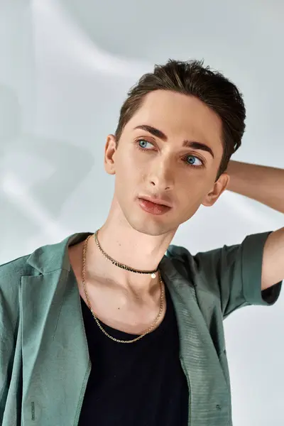 stock image A young man in a green jacket confidently poses, exuding pride and defiance. Studio setting, grey background.