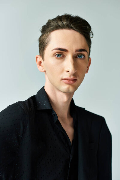 A vibrant, queer person in a black shirt strikes a confident pose in a studio setting, embracing his identity with pride.